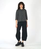 model in a black and white grid print blouse with 3/4 sleeves and a twin button detail, worn with wide leg black pant with a tapered ankle