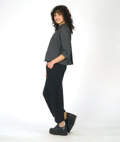 model in a black and white grid print blouse with 3/4 sleeves and a twin button detail, worn with wide leg black pant with a tapered ankle