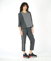 model in a black and white grid print straight leg pant, with a contrasting tuxedo stripe. worn with a matching pullover blouse with the center front panel in the same contrast as the tuxedo stripes, with 3/4 sleeves and a round neckline