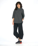 model in a black and white grid print top with an overlapping cowl neck and 3/4 sleeves, worn with a wide leg black pant with a tapered ankle