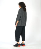 model in a black and white grid print top with an overlapping cowl neck and 3/4 sleeves, worn with a wide leg black pant with a tapered ankle