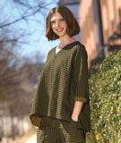 model in a black and yellow wide leg pant with a tapered ankle and oversized exterior pockets, worn with a matching pullover top with rolled long sleeves, a n-neck and the bodice split in to contrasting stripe directions