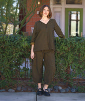 model in a black and yellow wide leg pant with a tapered ankle and oversized exterior pockets, worn with a matching pullover top with rolled long sleeves, a n-neck and the bodice split in to contrasting stripe directions