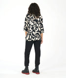 model in a black pullover blouse with an ivory floral print and 3/4 sleeves, a vneck, and a split at the front center seam. worn with a straight leg black pant