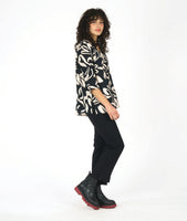 model in a black pullover blouse with an ivory floral print and 3/4 sleeves, a vneck, and a split at the front center seam. worn with a straight leg black pant