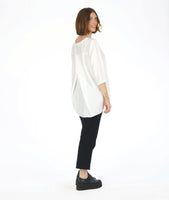 model in a slim black pant with a white 3/4 sleeve tunic with a rounded neckline with a v-split in the front center. top as a high-low hem