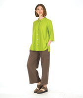 model in a slim brown pant with a lime green long button down blouse with 3/4 sleeves, with a twin button detail on the placket and sleeve cuffs