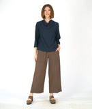 model in a straight leg brown pant with a navy blue pullover top with 3/4 sleeves and a cowl neck