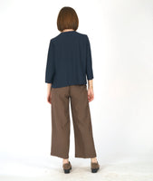 model in a straight leg brown pant with a navy blue pullover top with 3/4 sleeves and a cowl neck