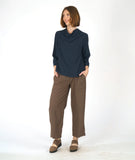 model in a straight leg brown pant with a navy blue pullover top with 3/4 sleeves and a cowl neck