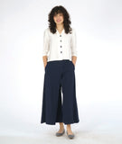 model in a white button down blouse with a 3/4 sleeve and splits on the sides, worn with a navy wide leg pant with an overlap at each leg