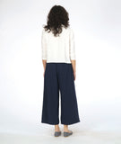 model in a white button down blouse with a 3/4 sleeve and splits on the sides, worn with a navy wide leg pant with an overlap at each leg