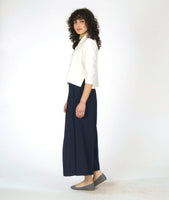 model in a white button down blouse with a 3/4 sleeve and splits on the sides, worn with a navy wide leg pant with an overlap at each leg