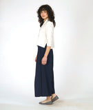 model in a white button down blouse with a 3/4 sleeve and splits on the sides, worn with a navy wide leg pant with an overlap at each leg