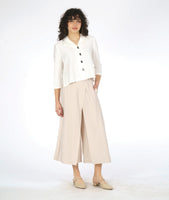 model in a white button down blouse with a 3/4 sleeve and splits on the sides, worn with an ivory wide leg pant with an overlap at each leg