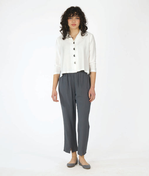 model in a short white button down with 3/4 sleeves, worn with a slim grey pant 