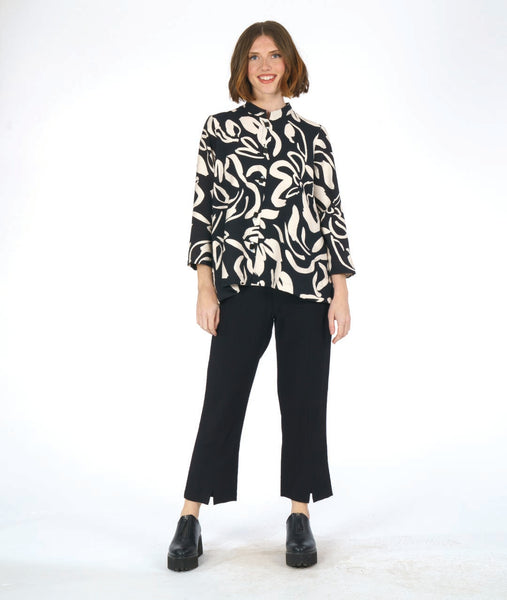 model in a slim cut black pant with a black button down blouse with a large ivory floral print