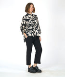 model in a slim cut black pant with a black button down blouse with a large ivory floral print