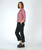 model in a black slim pant with a dusty pink button down blouse with 3/4 sleeves, a split cuff, and a twin button detailing