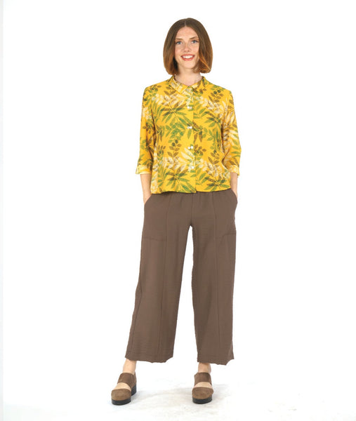 model in a brown pant with a yellow leaf print button down blouse with 3/4 sleeves, a split cuff, and a twin button detailing