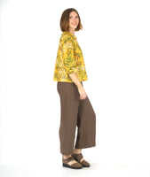 model in a brown pant with a yellow leaf print button down blouse with 3/4 sleeves, a split cuff, and a twin button detailing