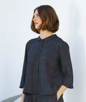 model in a black and grey striped button down blouse with a 3//4 sleeve and a black twin button detail. worn with a matching pant