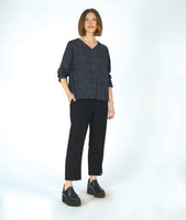 model in a slim black pant with a black and grey striped pullover top with long sleeves and a v-neck