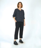 model in a slim black pant with a black and grey striped pullover top with long sleeves and a v-neck
