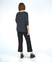 model in a slim black pant with a black and grey striped pullover top with long sleeves and a v-neck