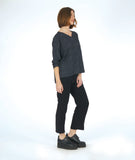 model in a slim black pant with a black and grey striped pullover top with long sleeves and a v-neck
