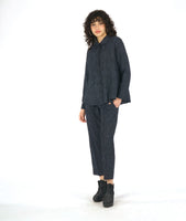 model in a grey and black striped pant with a contrasting tuxedo stripe, worn with a matching button down blouse with long sleeves and a full body with contrasting godets