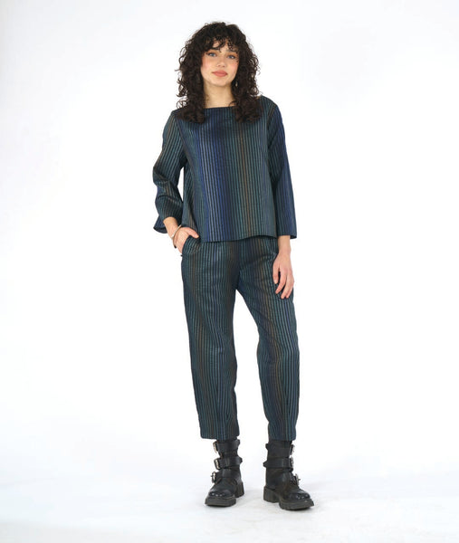 model in a slim striped pant with a matching boxy top with a full body and sleeve. fabric for top and pant are striped in varying shades of blue