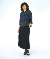 model in a boxy button down blouse with a 3/4 sleeve and twinbutton detail. fabric is striped with varying shades of blues. worn with a wide leg black pant