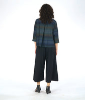 model in a boxy button down blouse with a 3/4 sleeve and twinbutton detail. fabric is striped with varying shades of blues. worn with a wide leg black pant