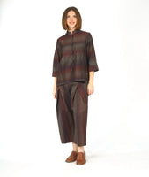 model in a button down blouse with a 3/4 sleeve with a split cuff, a double collar and a striped print in varying shades of reds and browns. worn with a matching wide leg pant with a double overlap at the top of each leg