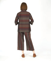 model in a button down blouse with a 3/4 sleeve with a split cuff, a double collar and a striped print in varying shades of reds and browns. worn with a matching wide leg pant with a double overlap at the top of each leg