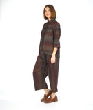 model in a button down blouse with a 3/4 sleeve with a split cuff, a double collar and a striped print in varying shades of reds and browns. worn with a matching wide leg pant with a double overlap at the top of each leg