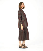 model in a button down blouse with long sleeves, a standing collar, and contrasting directional panels on the body. fabric is striped with varying shades of reds and browns. worn with a matching pant with an overlapping detail at either leg top