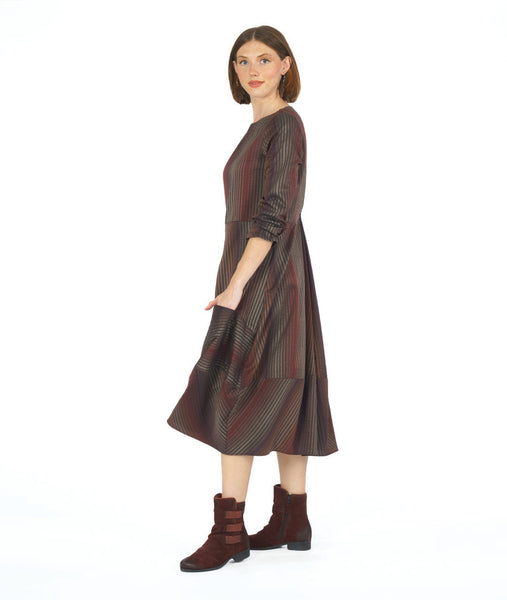 model in a striped dress with long sleeves and contrasting panels at the skirt. dress is striped with varying shades of red and brown