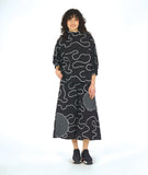 model in a wide leg black pant with contrasting round patches in a black and white grid print. worn with a matching pullover blouse with a standing cowl neckline, dropped shoulders, princess seams and a full boxy body. pants and top are black with a white swirl print embroidered all over