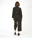 model in a wide leg pant with low pockets, worn with a matching blouse with long sleeves and a standing mandarin style collar. pants and blouse are both black with a yellow swirl pattern embroidered all over