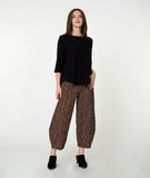 Woman wearing a black top and patterned brown pants on a white background