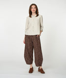 model in an ivory button down blouse with a brown print pant