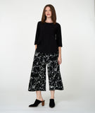 Woman wearing a black top and black and white marble print pants on a white background