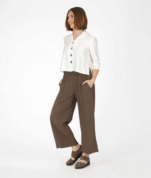 MODEL IN A STRAIGHT LEG BROWN PANT WITH A SHORT WHITE BUTTON DOWN