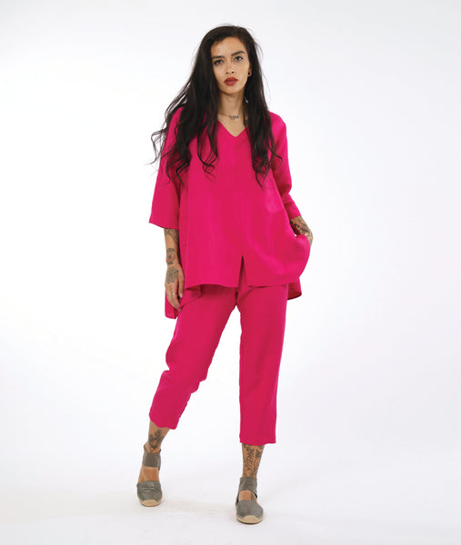 model in a hot pink slim cropped pant, with a matching tunic length pullover top with a 3/4 sleeve, vneck, slight hi-low hem, and a split at the center from hem