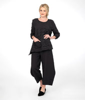 model in a black textured wide leg pant with a matching black top, with a dropped hem on either side and a single hip pocket