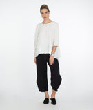 model in a black textured wide leg pant with a matching white top, with a dropped hem on either side and a single hip pocket