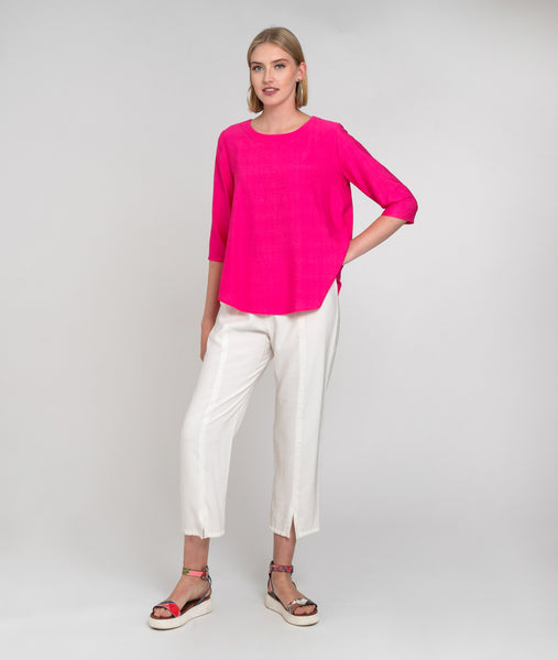 model in a hot pink pullover top with a slim, straight leg white pant with a  center seam and small split at the ankle 