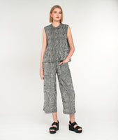 model in a black and white striped sleeveless button down blouse with a matching straight leg cargo pant